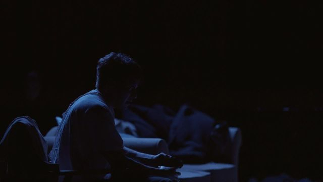 Omriss av person i mørke med svakt blått lys. Bilde fra forestilling