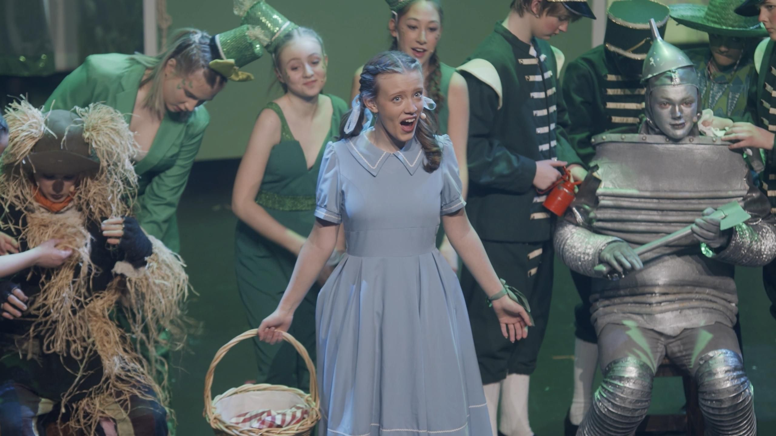 Fugleskremselet, Dorothy og Blikktømmerhoggeren omringet av folk i grønne kostymer