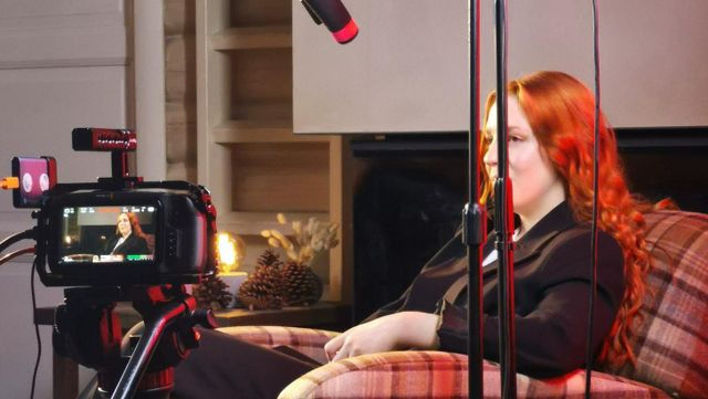 Kvinne i lenestol med mikrofon og filmkamera